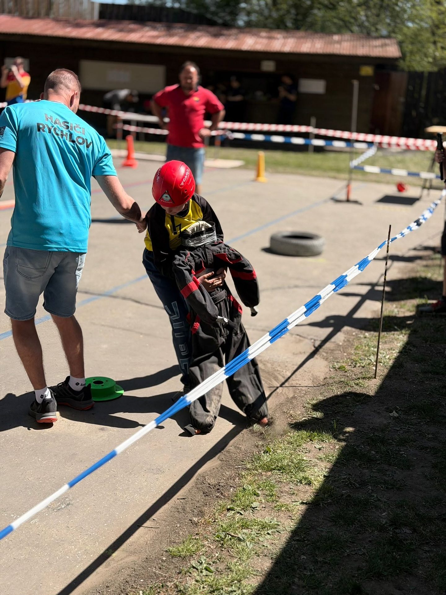 Závodník v červené přilbě při práci s hadicí